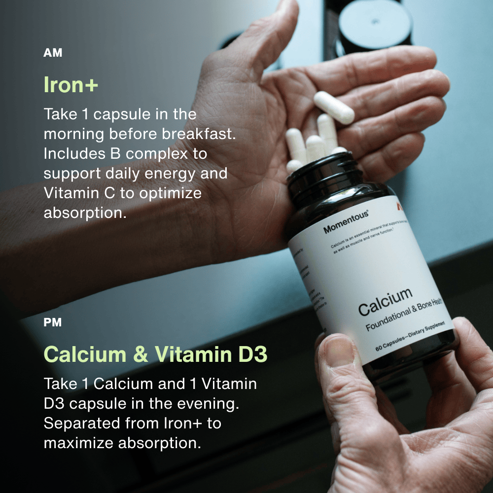 A person holds white capsules in one hand and a Momentous The Women’s Three™ bottle in the other, following directions to take their morning Iron supplement and evening Calcium with Vitamin D3 as part of the Momentous daily health system.