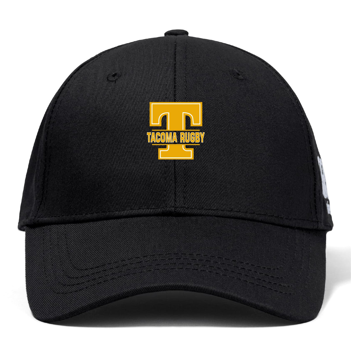 The EMB Canterbury Tacoma Tsunami Rugby Flexfit Drill Cap features a black design with a gold "T" and "TACOMA RUGBY" embroidered on the front.