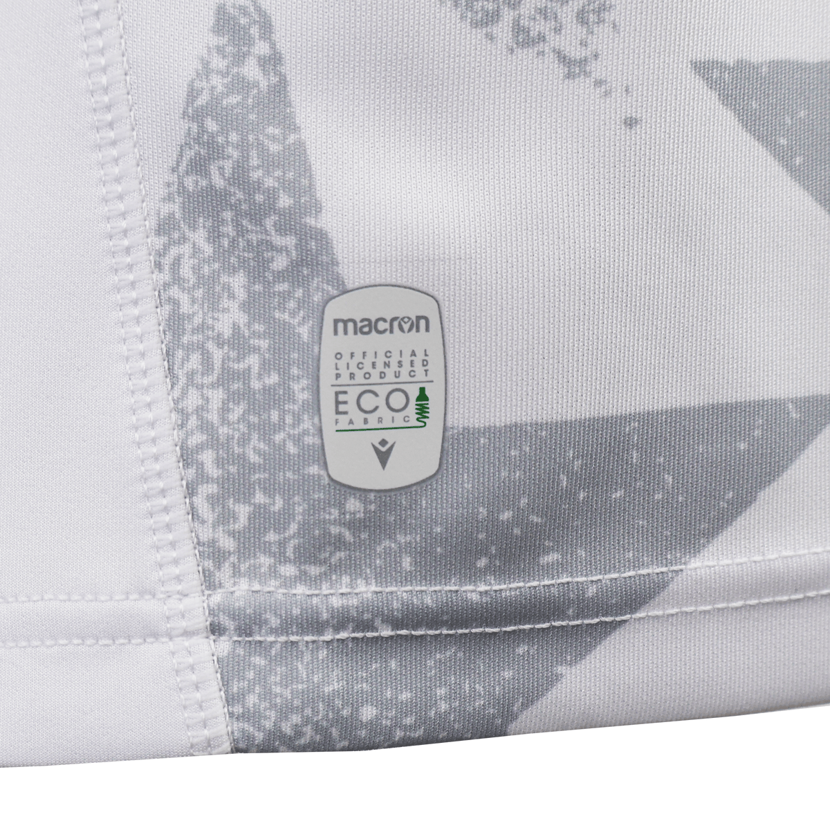 Close-up of the Women's USA Rugby WRWC25 Replica Away Jersey by Macron, showing the "Macron Official Licensed Product ECO Fabric" label on white and grey patterned fabric—ideal for fans seeking a sustainable replica jersey.