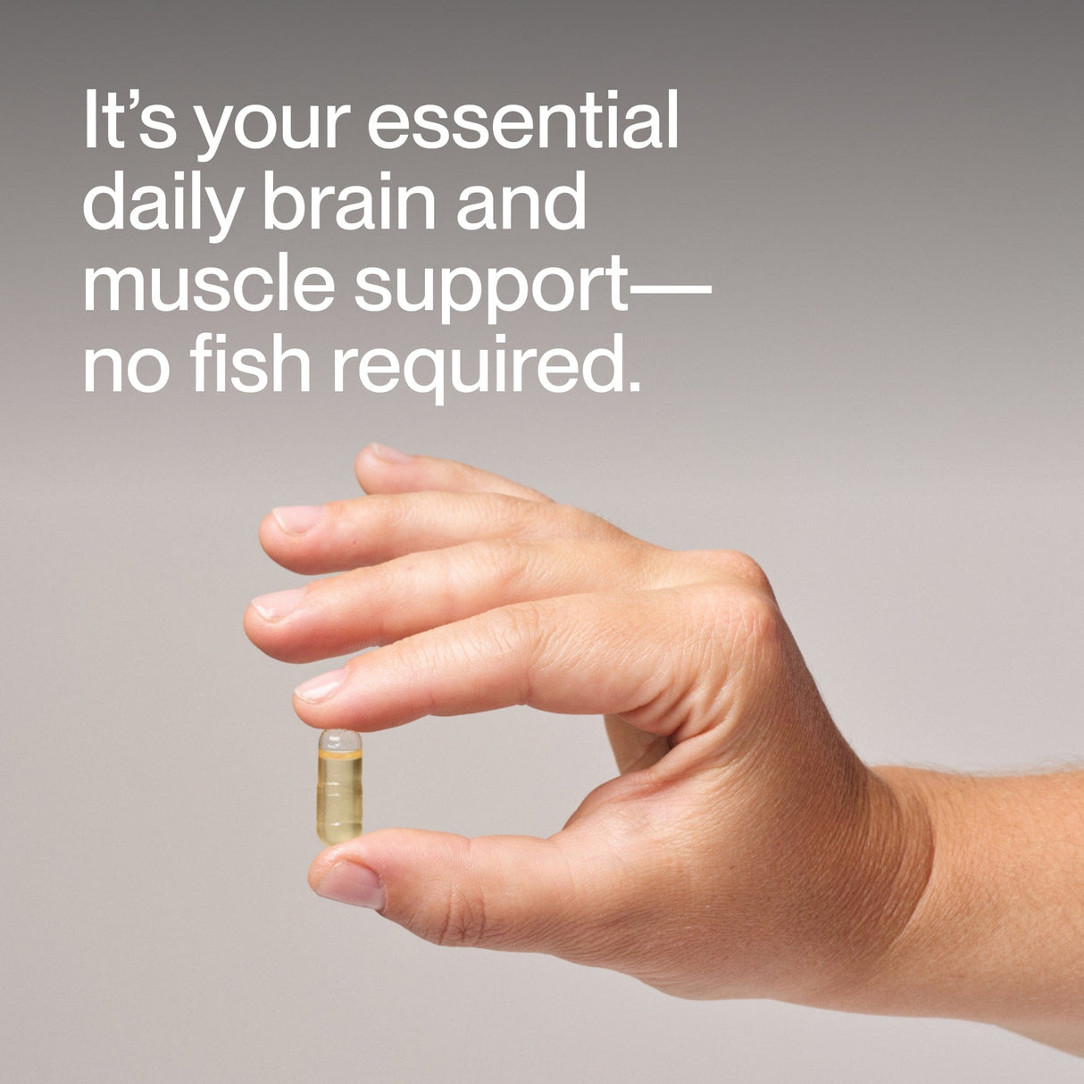 A hand holds a clear capsule of Momentous Vegan Omega-3 with the text, "Your essential daily brain and muscle support—powered by plant-based omega-3, no fish required," on a neutral background.