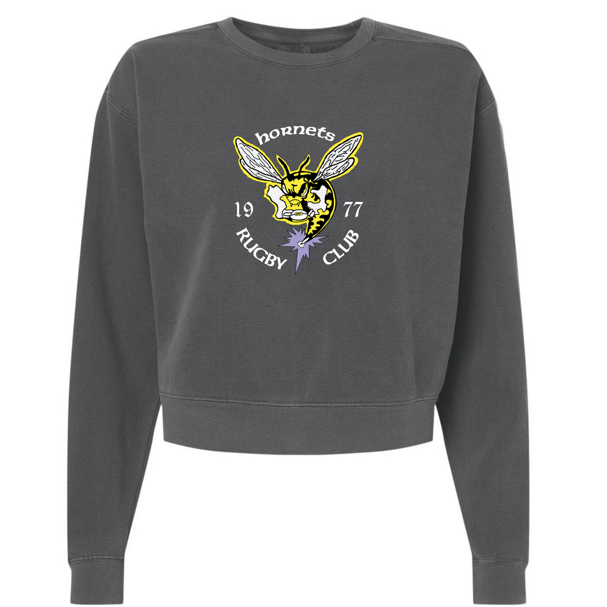 The EMB S&S Activewear Hornets Rugby Club 1977 Women's Garment-Dyed Mid-Length Crewneck Sweatshirt is a heavyweight fleece in charcoal gray, featuring a hornet graphic with "Hornets Rugby Club 1977" text and a purple flower below the hornet's head.