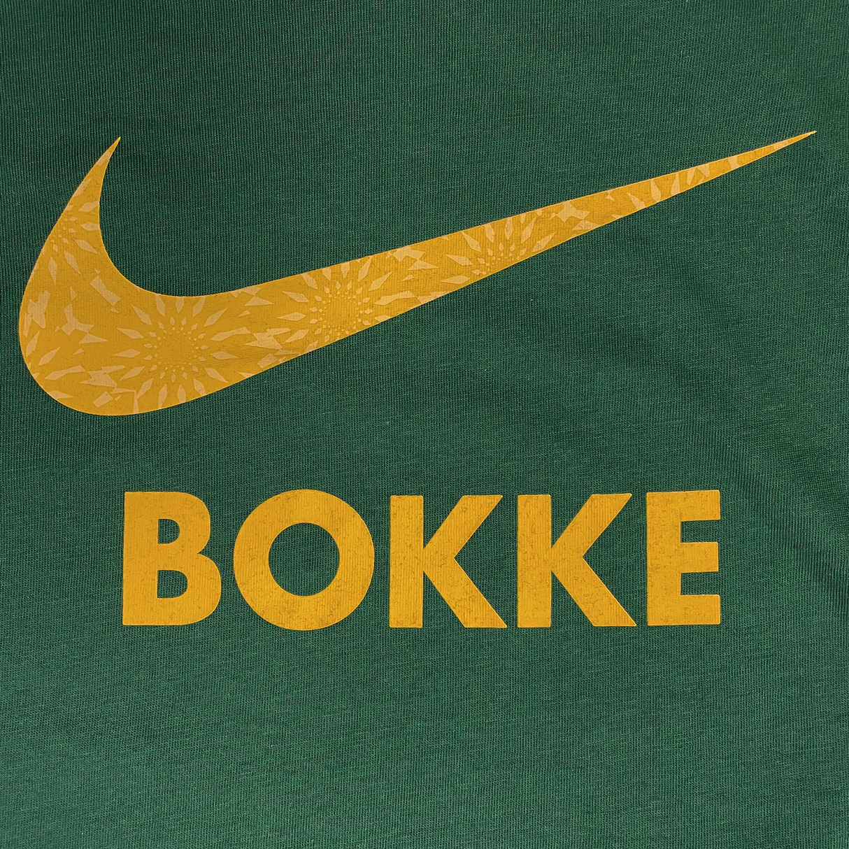 The Nike Youth Springboks 25 Bokke T-Shirt features green fabric, a yellow Nike swoosh, and "BOKKE" in bold yellow—perfect for any South Africa Rugby fan.