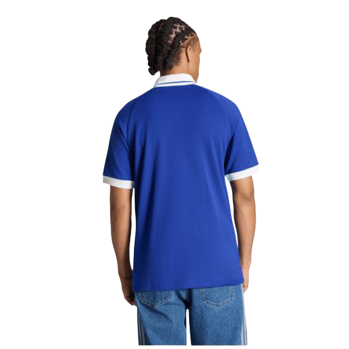 Person with braided hair wearing the adidas France FFR 26/27 Travel Polo—a blue short-sleeve polo with white trim—paired with blue jeans, standing with their back facing the camera.