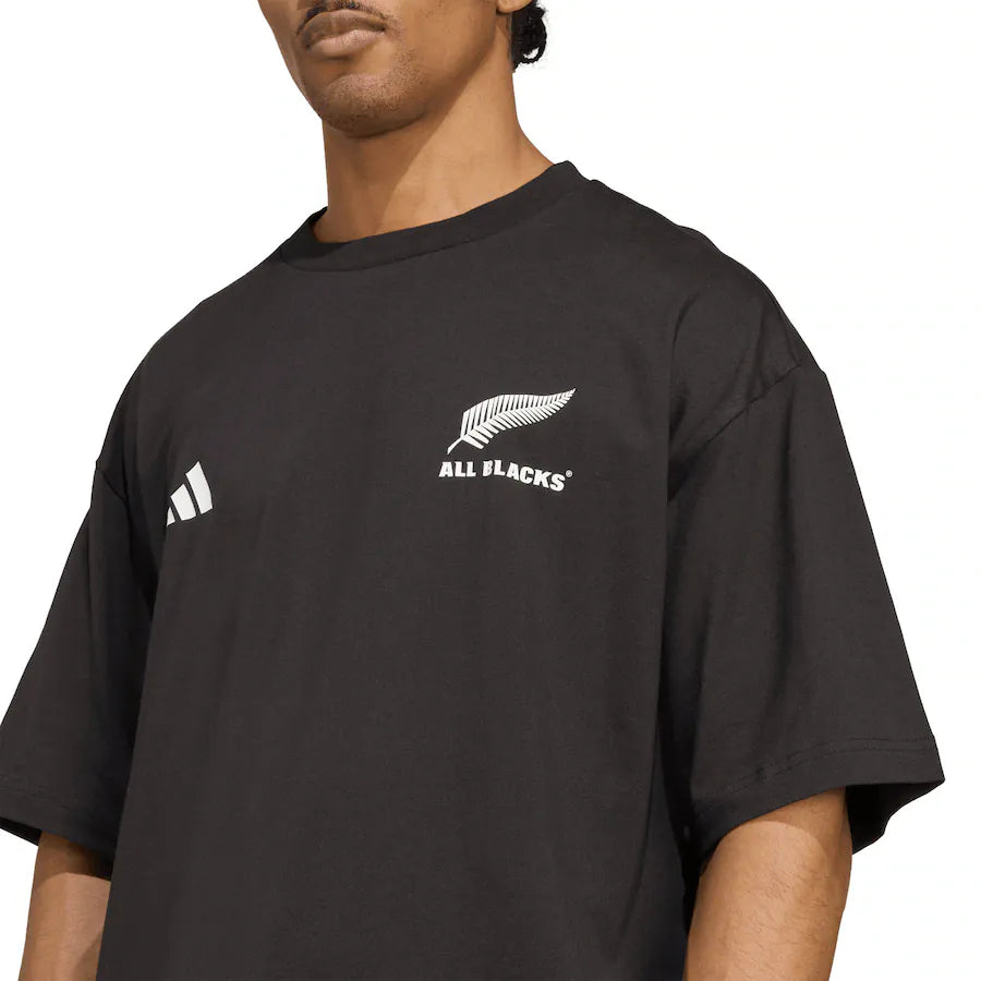 A person wearing the All Blacks 25/26 Presentation T-Shirt by adidas, featuring the adidas logo and silver fern emblem on the chest.
