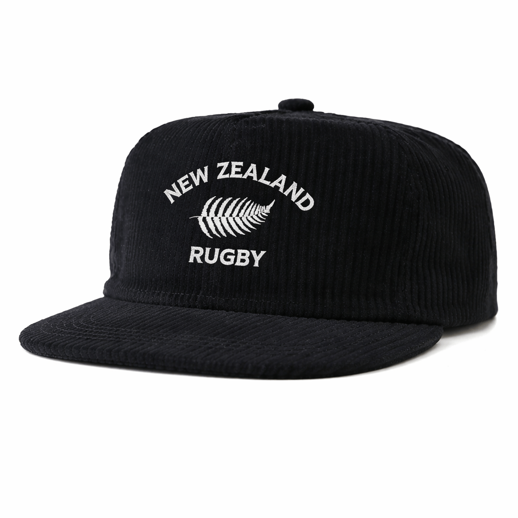 The Nations of Rugby New Zealand Corduroy Field Trip Cap by EMB Weld is a black corduroy cap with a flat brim, featuring “NEW ZEALAND RUGBY” and a white embroidered silver fern on the front. Part of the Nations of Rugby Collection.