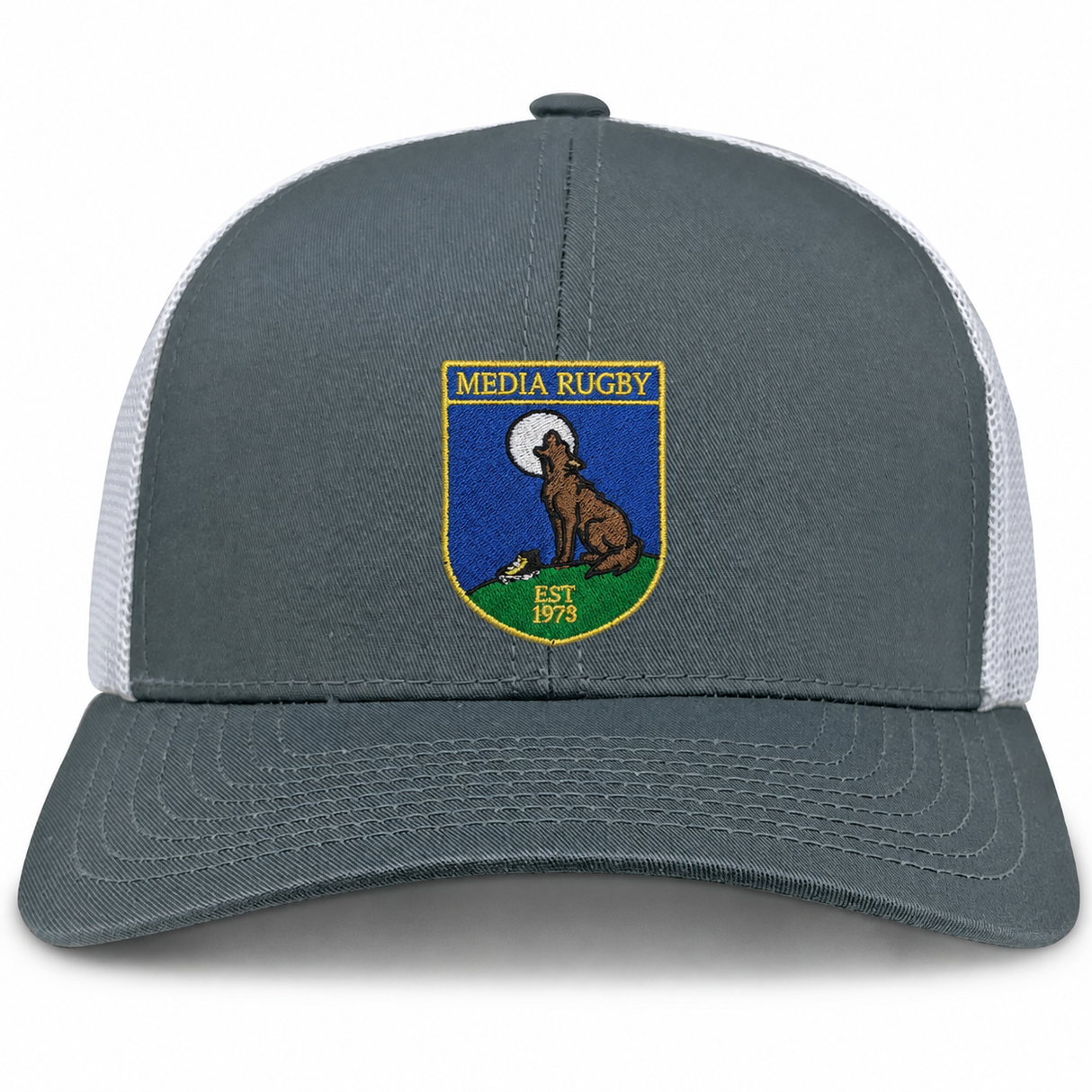 The Media Rugby Retro Trucker Cap by EMB S&S Activewear features a gray and white design with a front patch depicting a howling wolf, a full moon, and the words “MEDIA RUGBY EST 1973.” It is finished with a classic snapback closure for an adjustable fit.