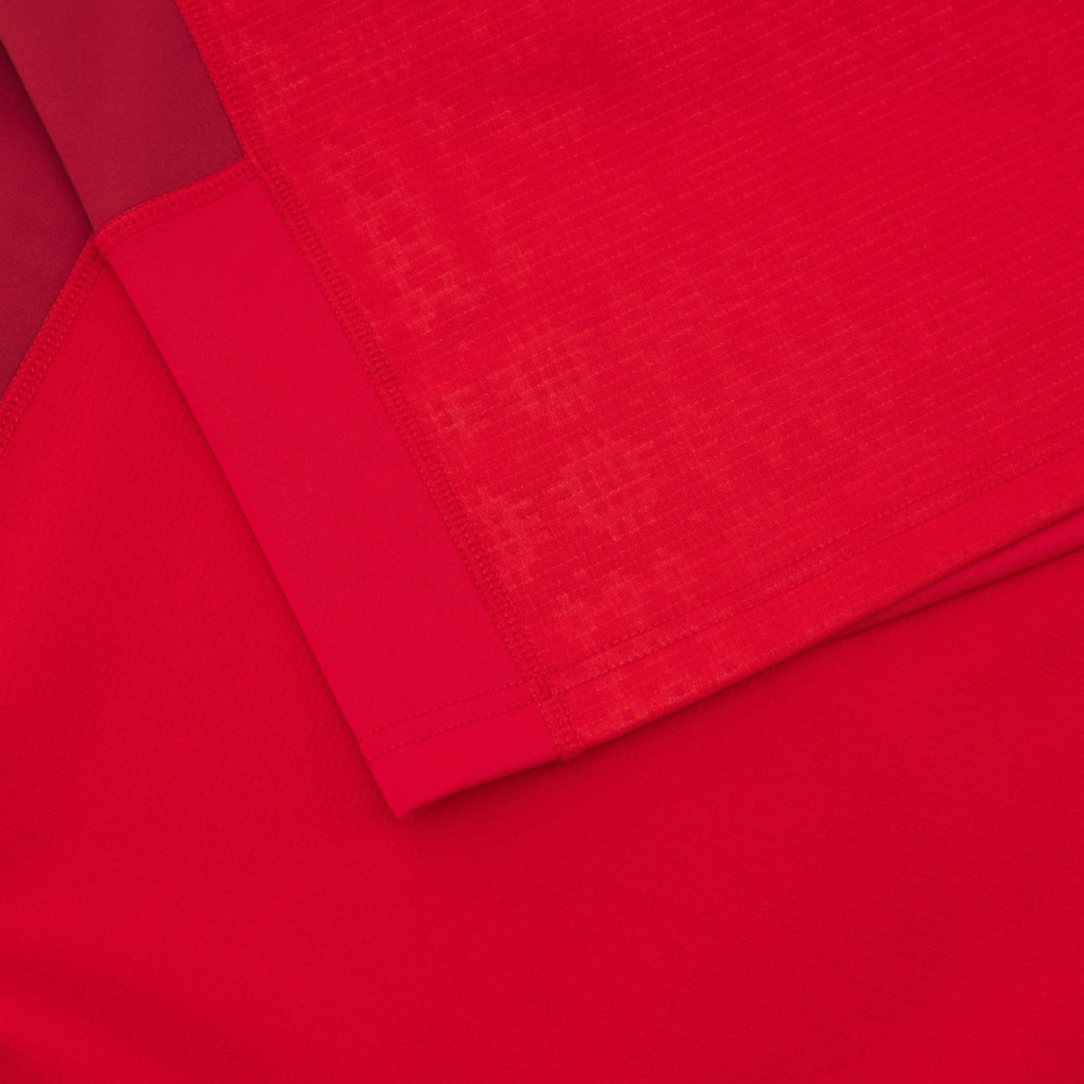 Close-up of overlapping red fabrics with varied textures, echoing the geometric patterns seen on the Wales 25/26 Authentic Matchday Home Jersey by Macron.