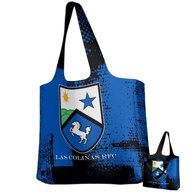 The Teamatical Las Colinas DNA Packable Zip Tote is a reusable blue tote featuring a shield emblem with horse, star, sun, and "LAS COLINAS RFC" text. Shown with its compact folded version—ideal for rugby fans seeking easy transport and style.