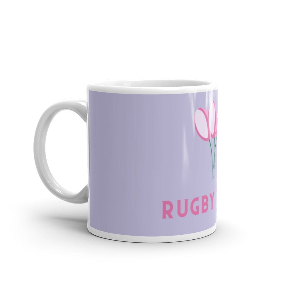 Side view of a lavender ceramic mug with white handle, pink 'Rugby' inscription and rugby ball flowers.