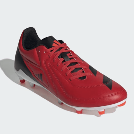 A red and black soccer cleat with white and red studs is shown against a light gray background.