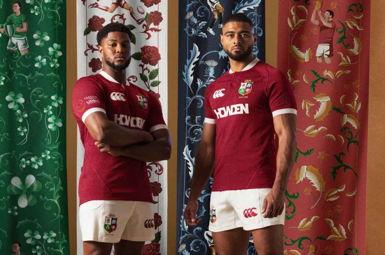 Two rugby players in maroon jerseys and white shorts stand in front of floral-patterned banners in green, blue, and red.