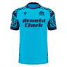The Scotland 25/26 Sky Training Jersey by Macron features a bright blue design, dark blue geometric shoulder pattern, "Arnold Clark" sponsor text on the front, and the Scottish Rugby logo on the upper left chest.