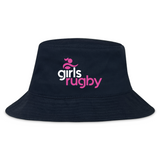 The Girls Rugby Crusher Bucket Cap by EMB S&S Activewear features black cotton twill with "girls rugby" in white and pink letters on the front and a pink abstract logo above, combining sporty style with sun protection.