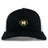 The Monarch Rugby Club Retro Trucker Cap by EMB S&S Activewear features a black and white design, an embroidered gold "M" rugby ball logo on the front, and an adjustable snapback closure.