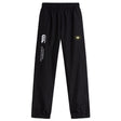 The Monarch Rugby Club Cuffed Hem Stadium Pant by EMB Canterbury features a black design with elastic waistband, cuffed hem, white logo, and a yellow "M" patch on the right leg—ideal for rugby or everyday athletic wear.