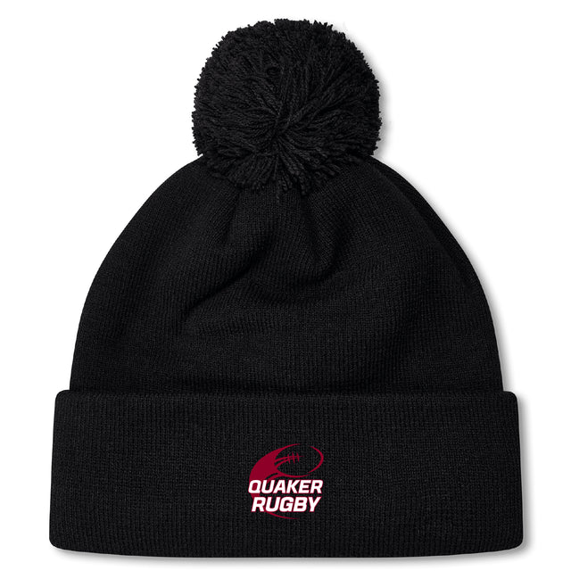 Stay warm in the Guilford College Pom Pom Beanie by EMB Canterbury, featuring a black knit design with fleeced lining, a top pom-pom, and "Quaker Rugby" logo in red and white on the front cuff.