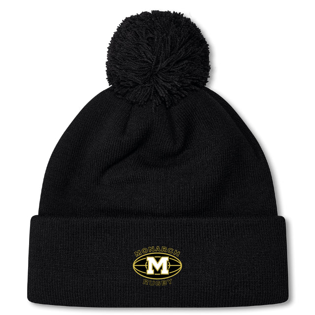The Monarch Rugby Club Pom Pom Beanie by EMB Canterbury is a black, fleece-lined hat with a pom-pom and an embroidered gold "M" Monarch Rugby logo on the front cuff.