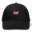 The Guilford College Flexfit Drill Cap by EMB Canterbury is a black cap with a curved brim, featuring a red and white "QUAKER RUGBY" logo and rugby ball graphic on the front for sporty style and comfort.