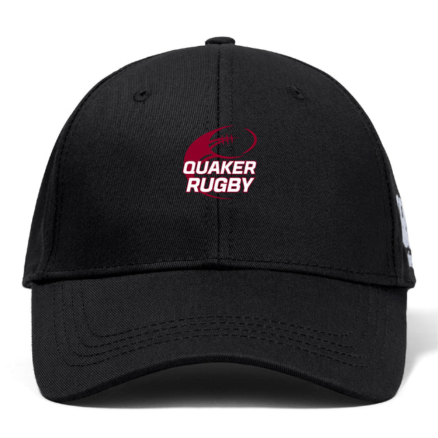 The Guilford College Flexfit Drill Cap by EMB Canterbury is a black cap with a curved brim, featuring a red and white "QUAKER RUGBY" logo and rugby ball graphic on the front for sporty style and comfort.