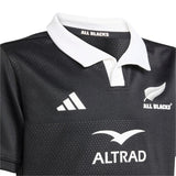 Close-up of the Youth All Blacks 25/26 Replica Home Jersey by adidas, featuring a white collar and displaying the iconic All Blacks logo, adidas branding, and Altrad sponsor.