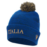 Show your support with the Italy 25/26 Supporters Pom-Pom Beanie by Macron—a blue knit beanie featuring "ITALIA," a gold embroidered logo, and brown pompom. Perfect for passionate Italy rugby fans.