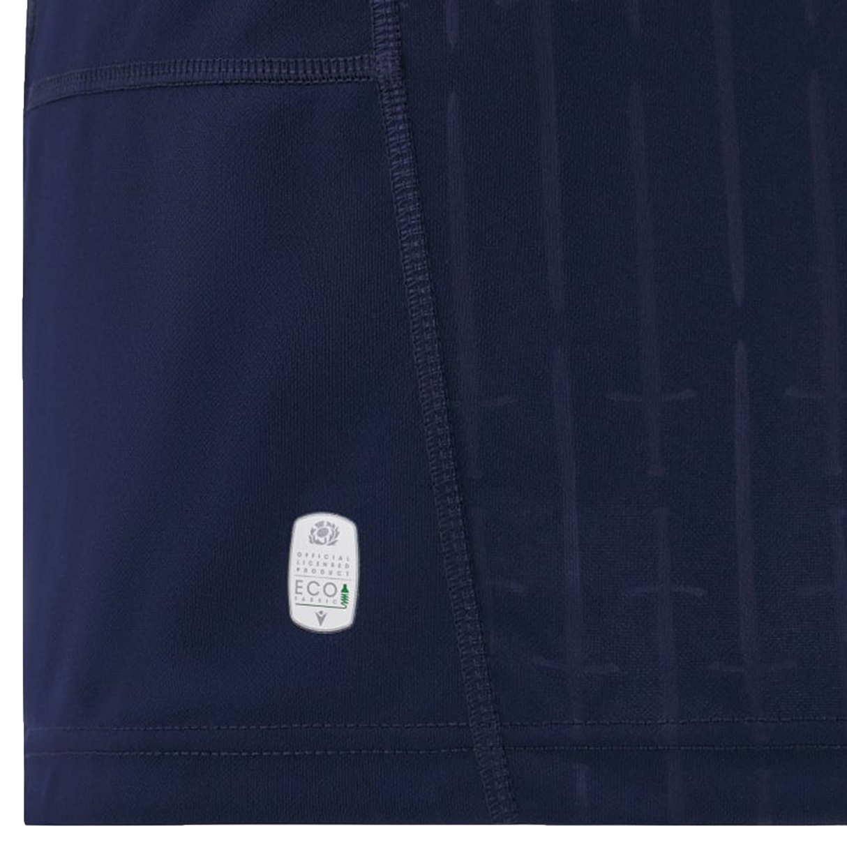 Close-up of a dark blue Scotland Replica Home Jersey 24/25 by Macron, featuring a small white label indicating eco-friendly material and a vertical pattern. Part of a pocket is visible on the left side, making this 2024/25 Replica Home Jersey both stylish and sustainable.