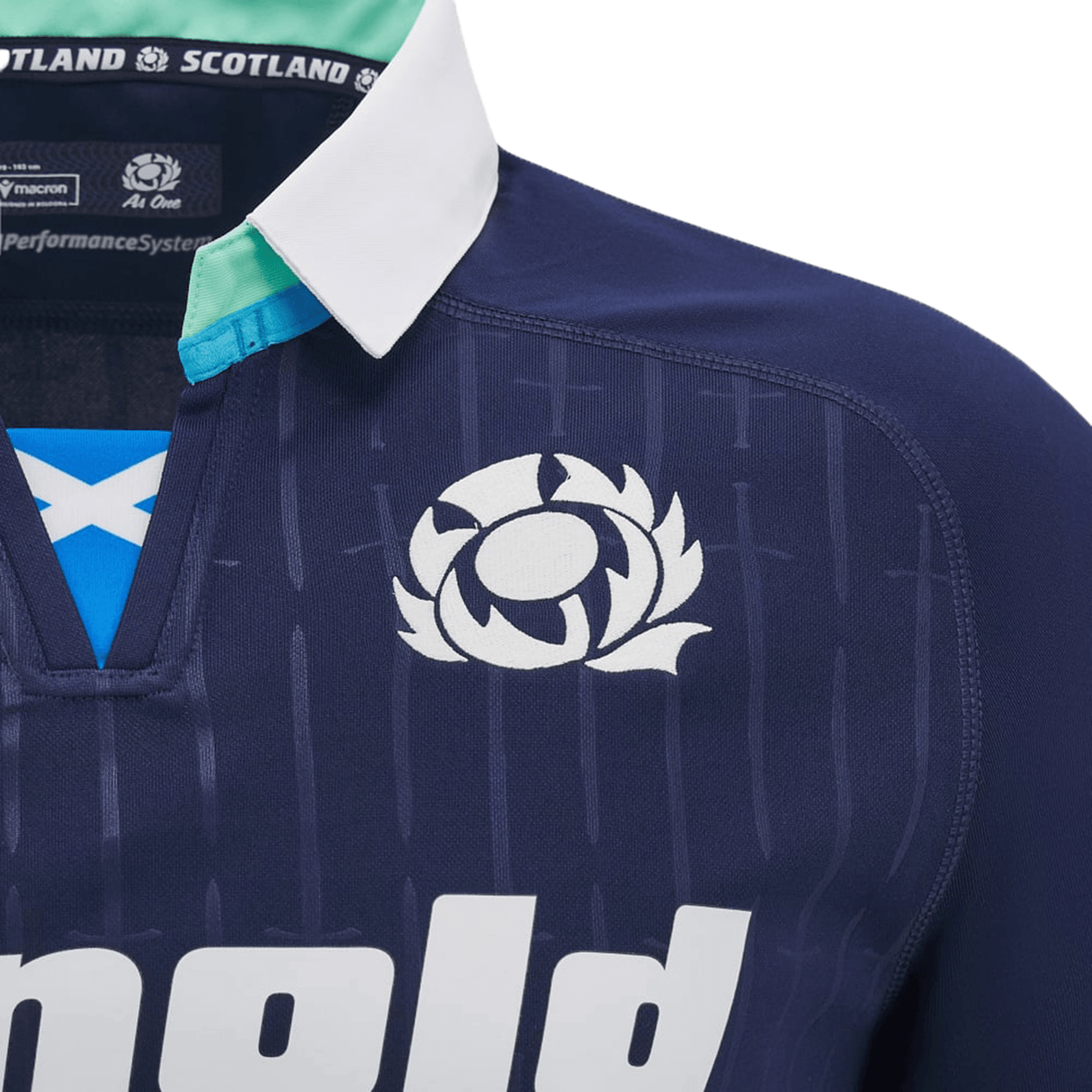 Close-up of a navy blue Scotland Rugby Jersey, the 2024/25 Scotland Replica Home Jersey by Macron, featuring a white thistle emblem above the text "Scotland" and a crisp white collar.