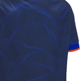 Close-up of a blue textured fabric with an orange and blue stripe on the edge of a sleeve, reminiscent of the iconic Edinburgh 24/25 Replica Home Jersey by Macron.