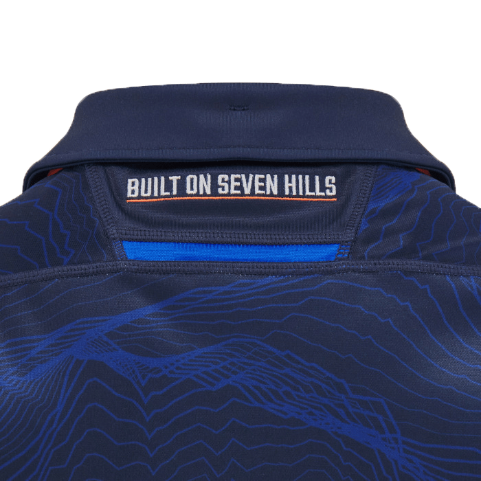 Close-up of the back of a navy Edinburgh 24/25 Replica Home Jersey by Macron, showcasing a pattern with the phrase "BUILT ON SEVEN HILLS" near the collar, encapsulating the essence of this iconic shirt.