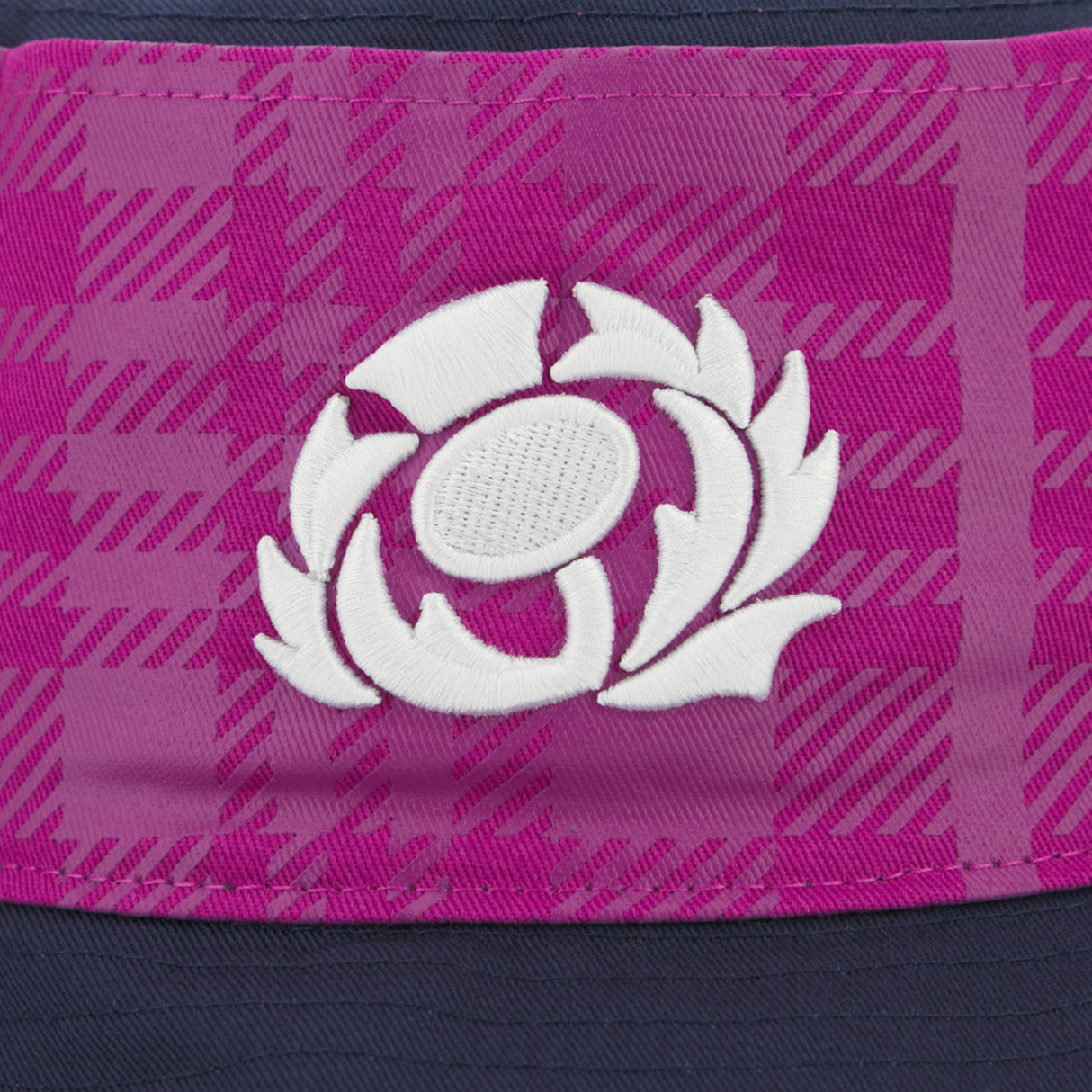 Close-up of a white thistle emblem embroidered on a pink and purple tartan Scotland 25/26 Bucket Hat by Macron.