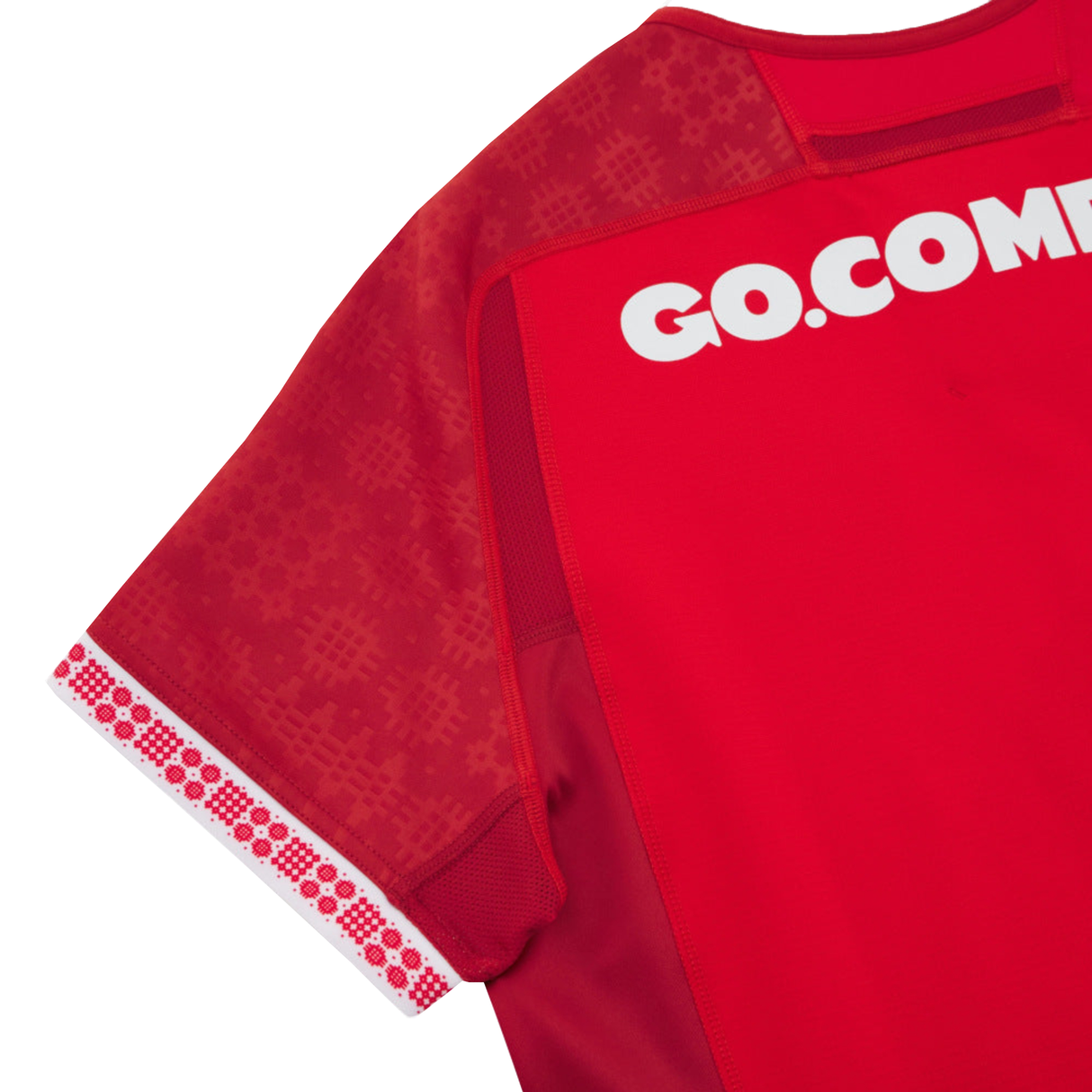 The Wales 25/26 Authentic Matchday Home Jersey by Macron features a classic red design with patterned sleeves, decorative white and red cuffs, and partial "GO.COM" text on the upper back.