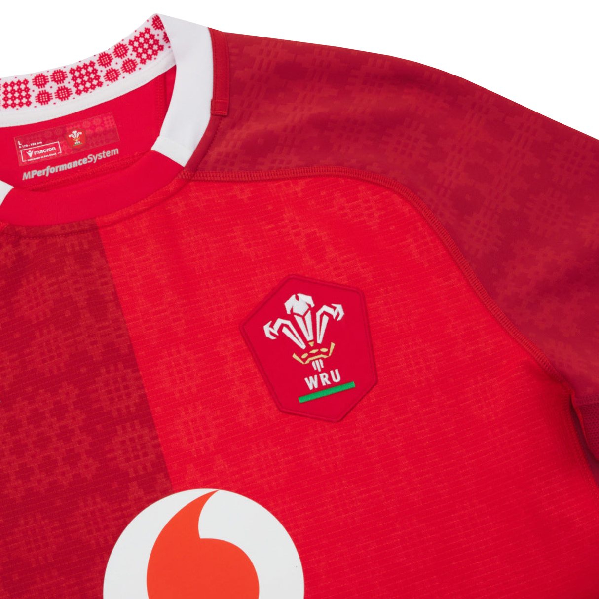 Close-up of the Wales 25/26 Authentic Matchday Home Jersey by Macron, a red rugby jersey featuring the WRU and Vodafone logos plus a patterned collar—official matchwear from Macron.