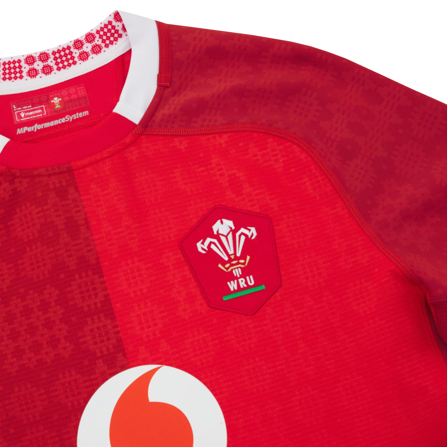 Close-up of the Wales 25/26 Authentic Matchday Home Jersey by Macron, a red rugby jersey featuring the WRU and Vodafone logos plus a patterned collar—official matchwear from Macron.