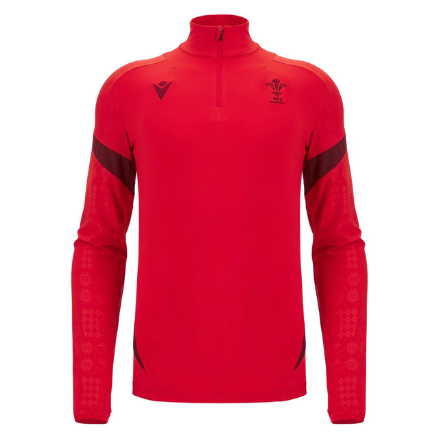 The Wales 25/26 Player 1/4 Zip Top by Macron is a red long-sleeve top featuring the Welsh Rugby Union logo and black accents on the shoulders and forearms.