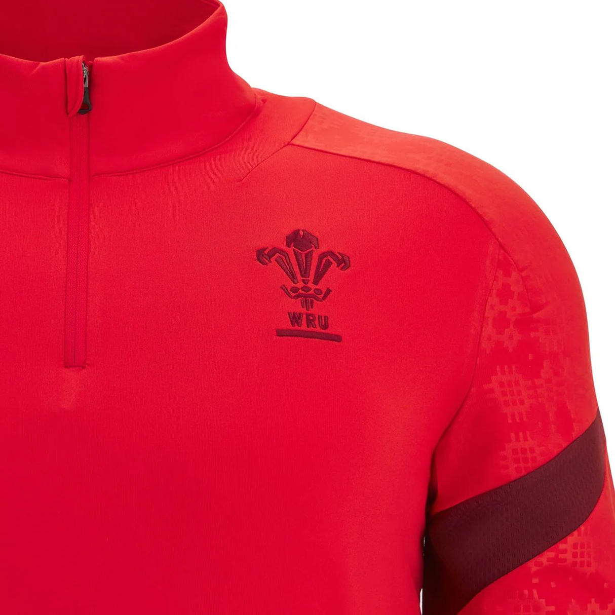 A close-up of the red Wales 25/26 Player 1/4 Zip Top by Macron, highlighting the WRU logo and chest emblem, and featuring a stylish half-zip collar.