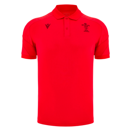 The Wales 25/26 Player Travel Poly Polo by Macron is a red short-sleeve collared polo featuring two embroidered black chest logos, set against a plain light grey background.