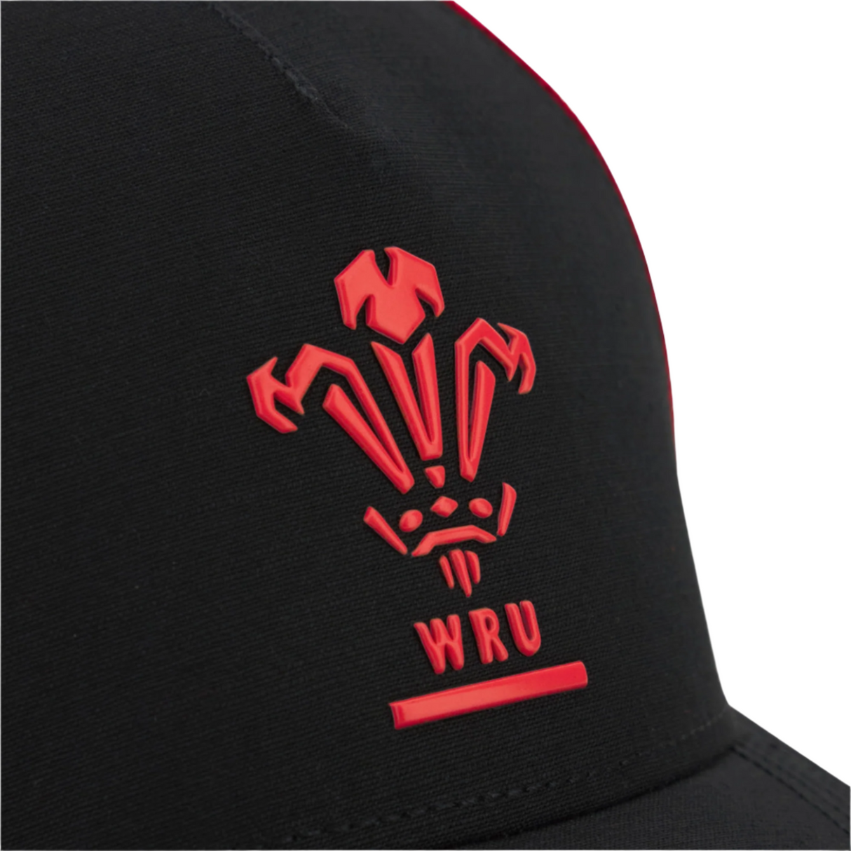 Close-up of the black Wales 25/26 Trucker Cap by Macron, featuring a red Welsh Rugby Union (WRU) logo and initials on the front.