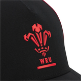 Close-up of the black Wales 25/26 Trucker Cap by Macron, featuring a red Welsh Rugby Union (WRU) logo and initials on the front.