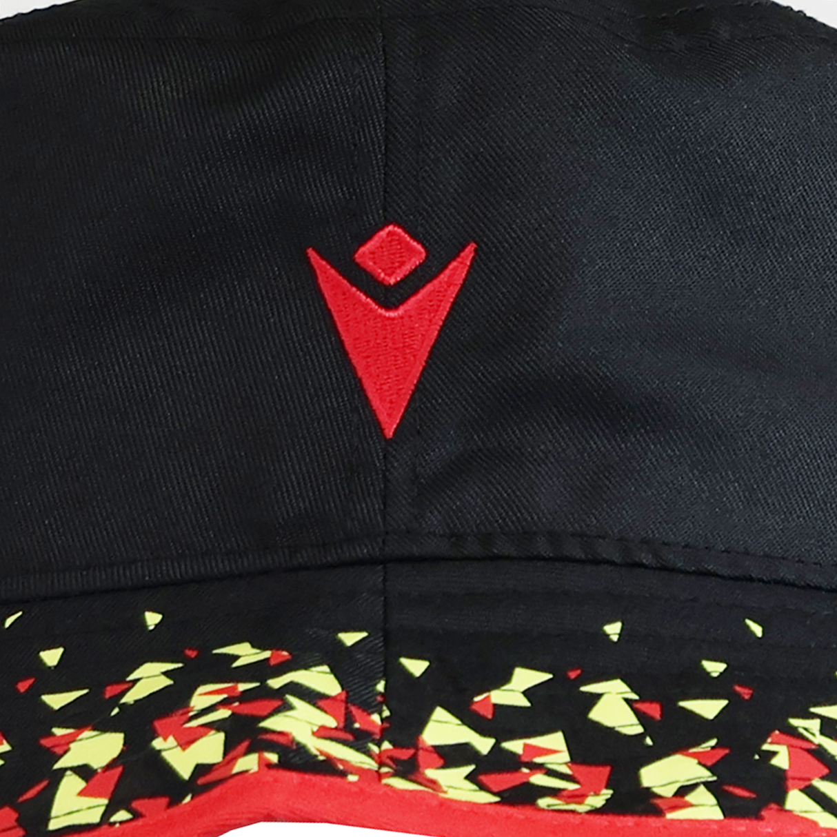 The Wales 25/26 Bucket Hat by Macron features black fabric with a red geometric logo and a pattern of yellow and red triangles, blending bold color with modern style.