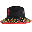 The Wales 25/26 Bucket Hat by Macron features a black base, red trim, red WRU logo, and a yellow and green geometric pattern around the brim.