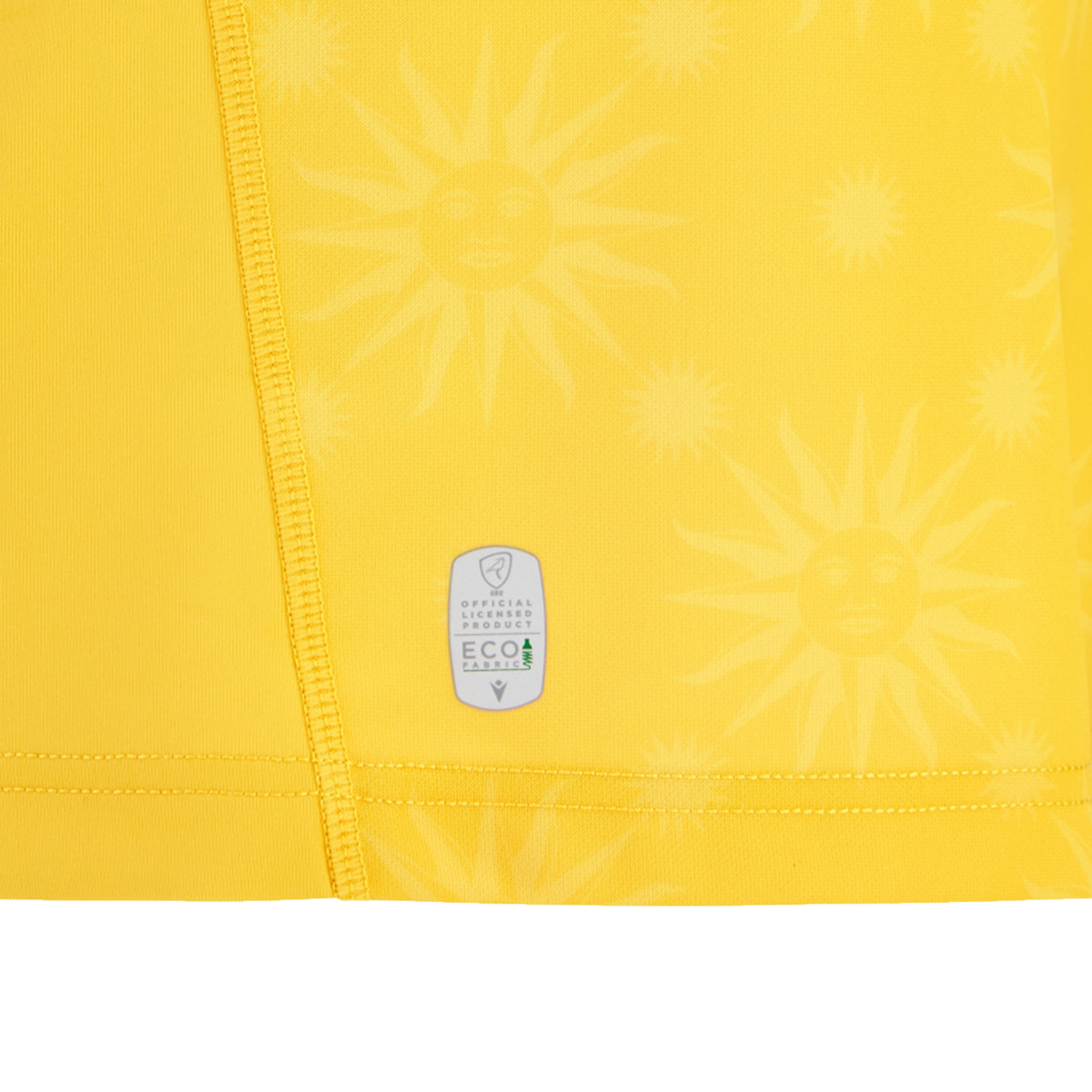 Close-up of yellow fabric with sun face patterns and visible stitching, featuring an EcoFightex label—recalling the fine details on the Uruguay URU 25/26 Replica Away Jersey by Macron.