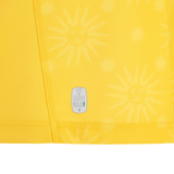 Close-up of yellow fabric with sun face patterns and visible stitching, featuring an EcoFightex label—recalling the fine details on the Uruguay URU 25/26 Replica Away Jersey by Macron.