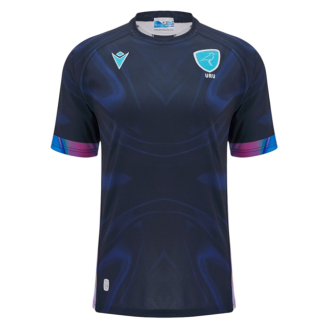 The Uruguay URU 25/26 Replica Training Jersey by Macron features short sleeves, dark blue color with subtle patterns, and light blue URU and Macron logos on the chest.
