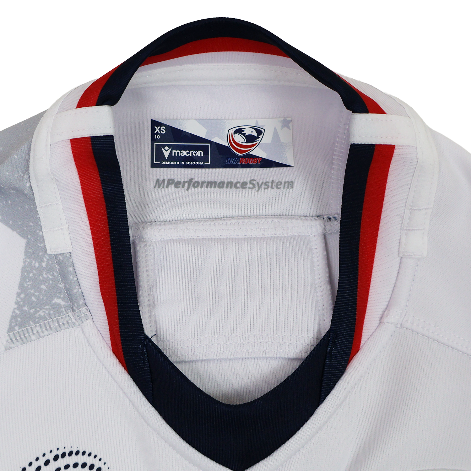 Close-up of the inside collar on the Women's USA Rugby WRWC 25 Away Bodyfit Shirt by Macron, featuring the Macron brand tag, USA Rugby logo, and "MPerformanceSystem" text for comfort and performance.