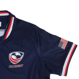 The Youth USA Rugby 24/25 Home WRWC Jersey by Macron features the team's logo on the chest, a small American flag patch on the sleeve, and red, white, and blue trim—perfect for young rugby fans.