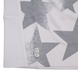 Close-up of a white fabric with large gray stars and a small "macron ECO" label near the hem, from the Youth USA Rugby WRWC 25 Home Jersey by Macron.