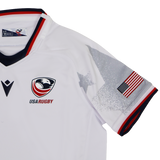 The Youth USA Rugby WRWC 25 Home Jersey by Macron features the team logo, WRWC 25 detail, an American flag sleeve patch, and grey star graphics on the shoulders.