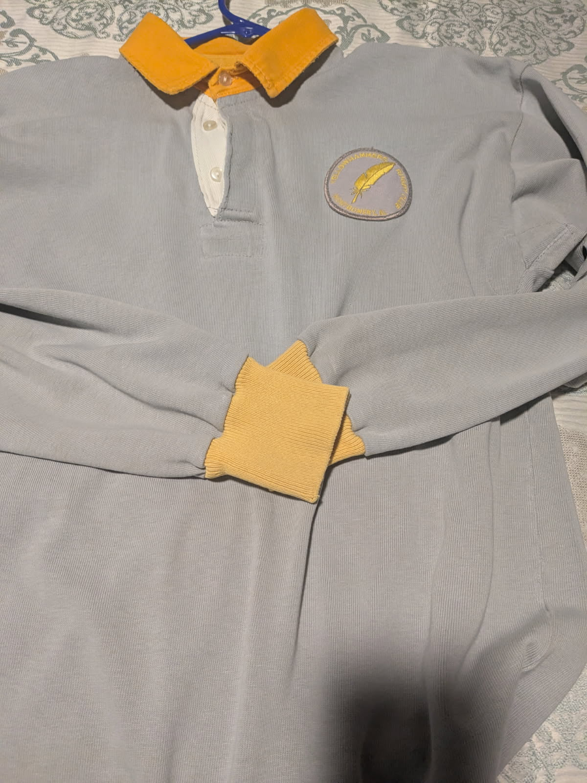 The Montgomery Yellowhammers Classic Canterbury Jersey by Custom CCC MUD is a light gray long-sleeve polo with yellow collar and cuffs, plus an embroidered yellow logo on the left chest. Order by 5/31.