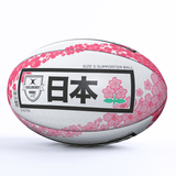 A **Japan Supporters Ball by Gilbert** adorned with pink floral designs and Japanese characters. The text includes "Japan Supporters Ball" and "Size 5 Supporter Ball," celebrating the Brave Blossoms. The iconic **Gilbert** logo is also prominently displayed.