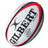 A Gilbert Orion Match Ball in white with red and black accents, featuring the Gilbert brand name, logo, and “9.5-10 PSI” marking, designed as an official match rugby ball for superior performance.